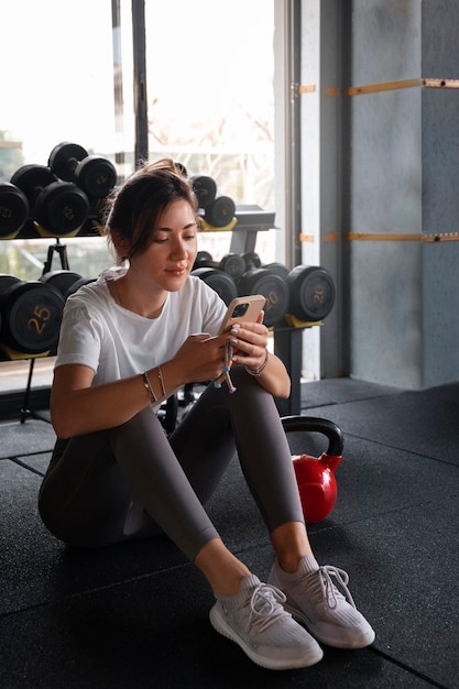 Smartphone della tenuta della donna della foto a figura intera