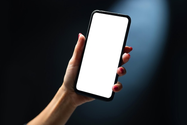 Smartphone della tenuta della mano con lo spazio bianco della copia sullo schermo. Persona di sesso femminile con il cellulare moderno