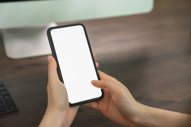 Smartphone della tenuta della mano della donna e schermo in bianco commovente.