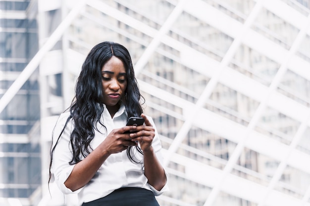 Smartphone di uso della donna dell&#39;afroamericano