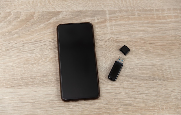 Smartphone e flash drive USB su un tavolo di legno