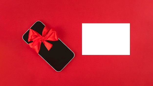 Smartphone e nota bianca vuota su sfondo rosso