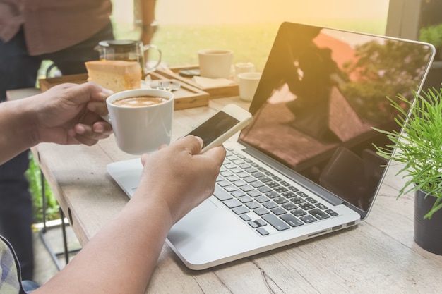 smartphone e tazza di caffè della mano dell&#39;uomo