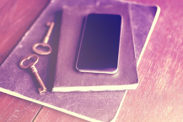 Smartphone in bianco con il diario e le chiavi di vecchio stile sul pavimento di legno