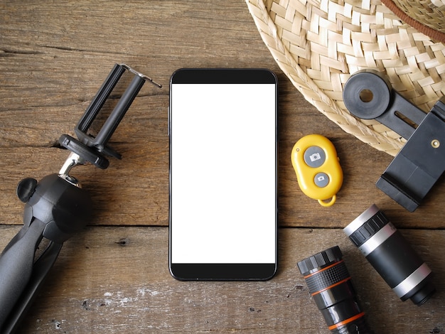 smartphone mobile con schermo bianco e accessori per lenti fotografiche sul tavolo di legno