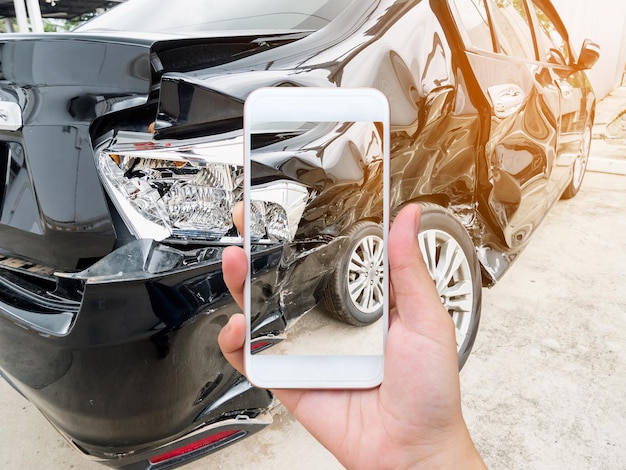 Smartphone mobile della tenuta femminile che fotografa l'incidente d'auto per l'assicurazione