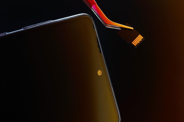 Smartphone spento e micro sd estratta con una pinzetta
