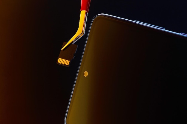Smartphone spento e micro sd estratta con una pinzetta