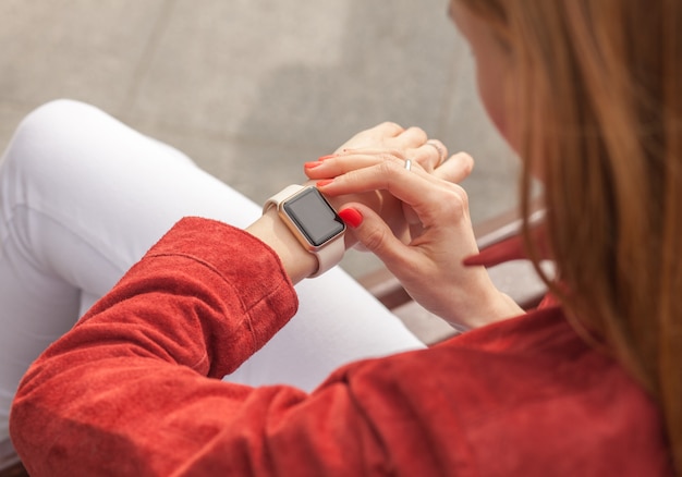 Smartwatch di uso della giovane donna con lo schermo in bianco all'aperto