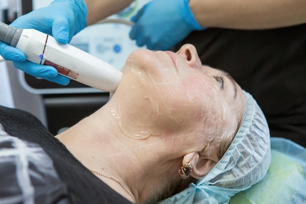 Smas lifting e ringiovanimento della pelle del viso di una donna anziana da un cosmetologo