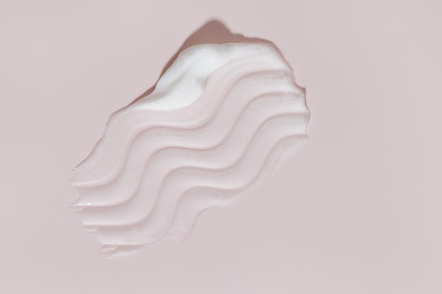 Smear di crema di bellezza bianca macchia su sfondo rosa crema per il viso lozione per il corpo swipe swatch