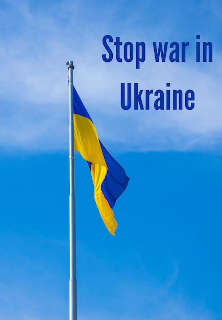 Smettete la guerra in Ucraina testo sulla bandiera nazionale ucraina sventola nel vento contro il cielo blu