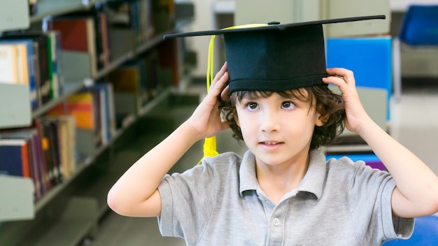 smiley ragazzo con cappello di laurea e stand di carta diploma