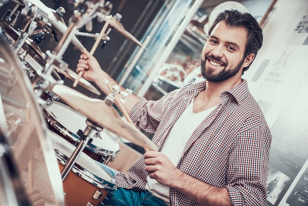 Smilling uomo barbuto in camicia gioca sul set di batteria.