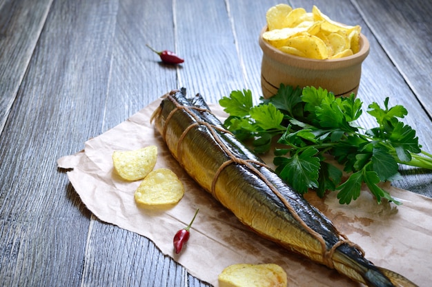 Snack alla birra. Pesce affumicato, patatine fritte su un tavolo di legno. Luccio sauro artigianale affumicato.