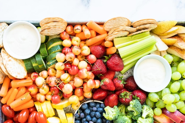 Snack board con frutta fresca, verdura, cracker e salse.