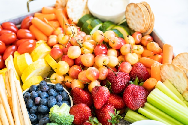 Snack board con frutta fresca, verdura, cracker e salse.