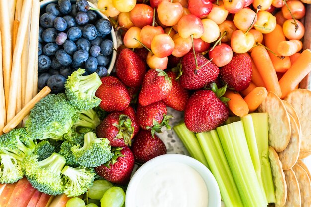 Snack board con frutta fresca, verdura, cracker e salse.