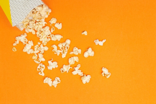 Snack concept Popcorn dolce fuoriuscito dal bicchiere di carta su sfondo arancione