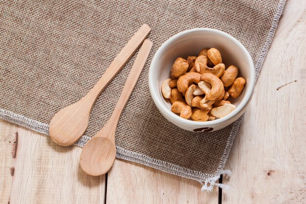 Snack di anacardi in ciotola di ceramica con cucchiai di legno