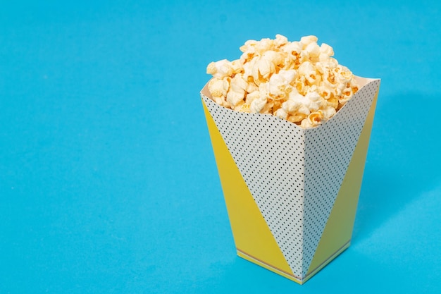 Snack di guardare il film concept Popcorn dolce in tazza di carta su sfondo azzurro