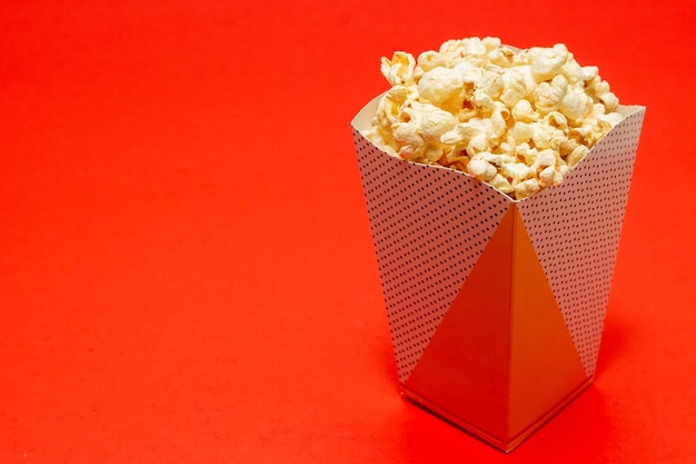 Snack di guardare il film concept Popcorn dolce in tazza di carta su sfondo rosso