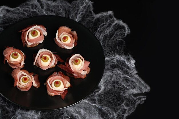 Snack originali di Halloween. Bulbi oculari di prosciutto cotto con mozzarella, olive ripiene al peperoncino