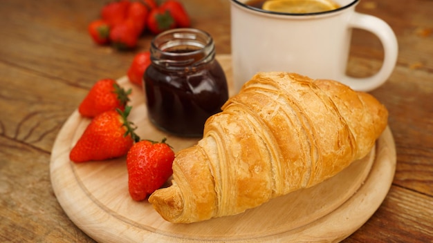 Snack tea break tè al limone croissant vasetto di marmellata e fragole fresche