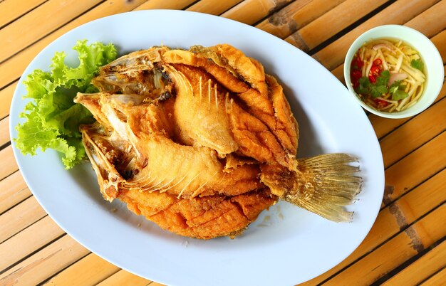 Snapper fritto con salsa di peperoncino rosso in piatto blu su sfondo di bambù