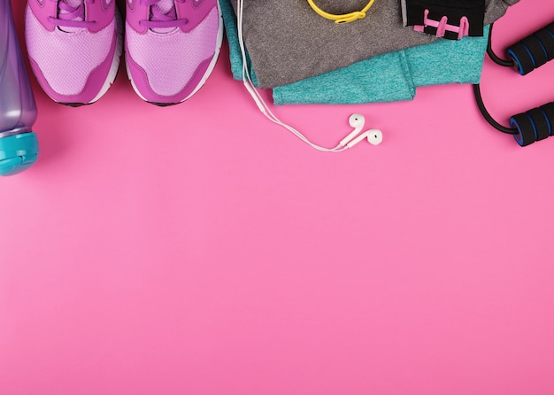 Sneaker da donna rosa, una bottiglia d'acqua, guanti e una corda per saltare per lo sport
