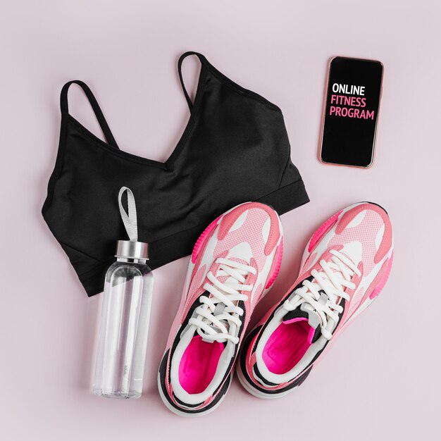 Sneakers da donna alla moda con smartphone su sfondo rosa. Programma di formazione online