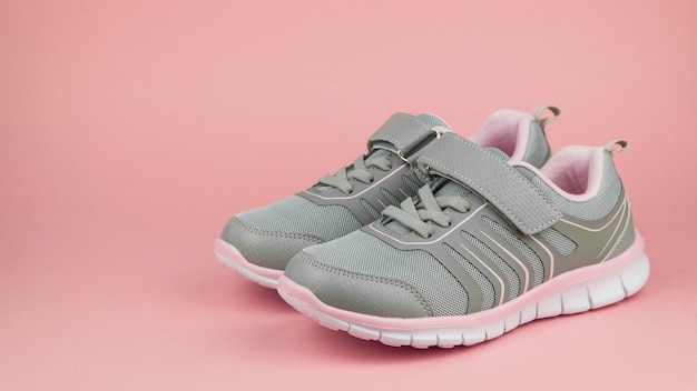 Sneakers da donna moda grigio e rosa su sfondo rosa pastello.