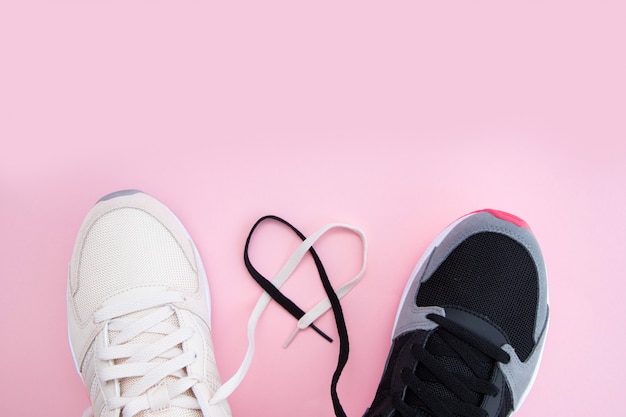 Sneakers e lacci bianchi e neri maschili e femminili a forma di cuore su uno sfondo rosa