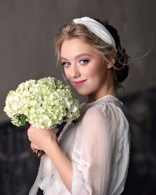 Snella sposa in abito da sposa vintage in Studio. Ritratto di una ragazza sorridente con un bouquet da sposa nelle sue mani