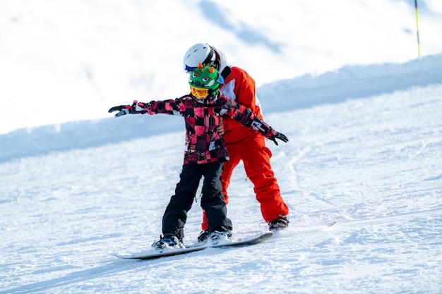 Snowboard School Boy con istruttore che impara lo snowboard