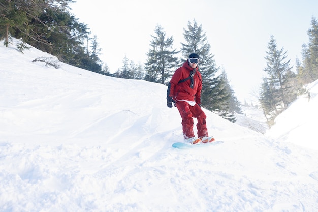 Snowboarder attivo che salta in montagna in una giornata di sole.