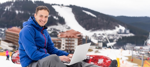 snowboarder che digita sul laptop in inverno in montagna