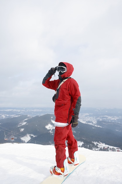 Snowboarder in piedi sulla sua tavola con vista su una pista da sci