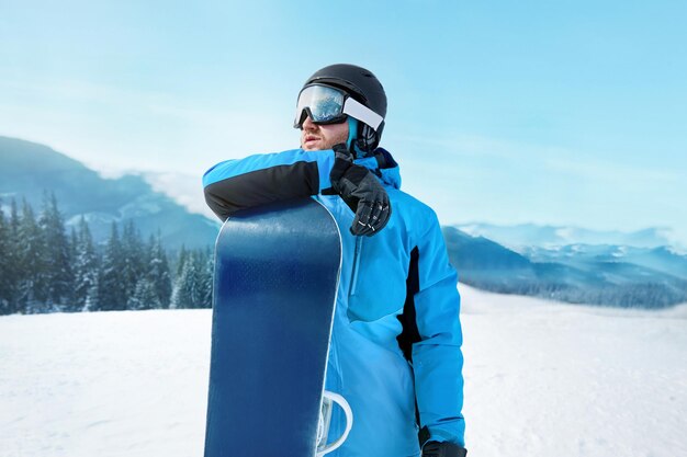 Snowboarder Of Man At Ski Resort On The Background Blue Sky Hold Snowboard Wearing Ski Glasses Ski Goggles With The Reflection Of Snowed Mountains