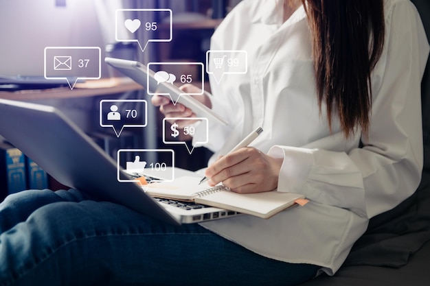 Social media e marketing icone virtuali concetto dello schermo primo piano della tastiera di battitura della donna d'affari con il computer portatile xA