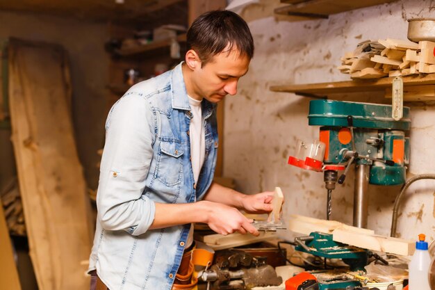 Soddisfatto, allegro, gioioso e sorridente woodmaster è in piedi vicino al desktop nella sua officina, workstation