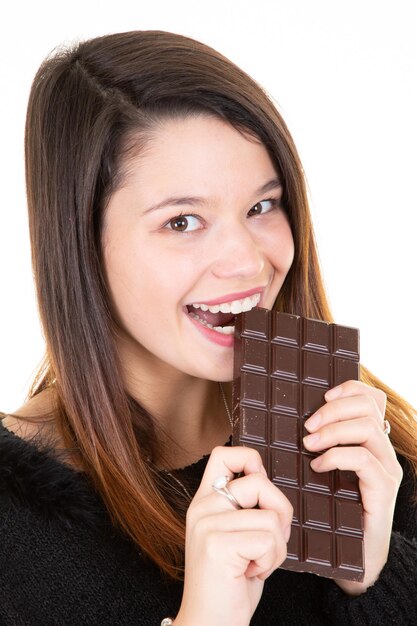 Soddisfatto bella ragazza mordere la barra di cioccolato sorridente