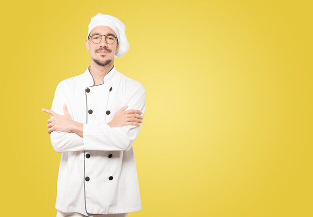 Soddisfatto giovane chef con le braccia incrociate gesto