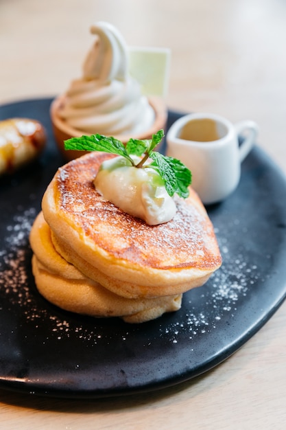 Soffici pancakes serviti con banana caramellata, gelato e sciroppo.