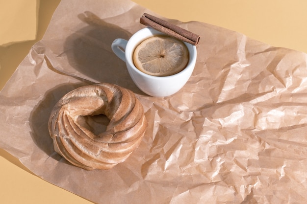 Soffio fresco sul tavolo con una tazza bianca di tè e limone sullo sfondo arancione pastello