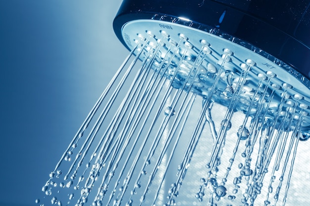 Soffione doccia con flusso d'acqua su sfondo blu