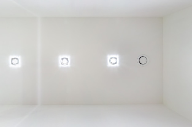 Soffitto sospeso con lampade alogene e costruzione in cartongesso in una stanza vuota in appartamento o casa Soffitto teso bianco e di forma complessa