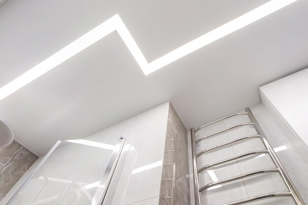 Soffitto sospeso con lampade alogene e costruzione in cartongesso in una stanza vuota in appartamento o casa Soffitto teso bianco e di forma complessa