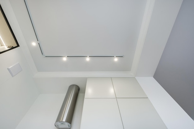 Soffitto sospeso con lampade alogene e costruzione in cartongesso in una stanza vuota in appartamento o casa Soffitto teso bianco e di forma complessa