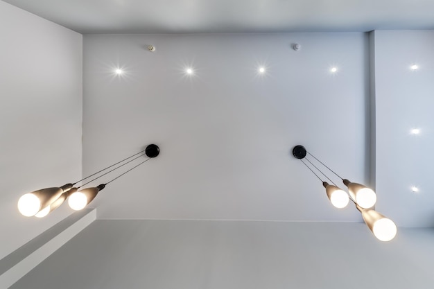 Soffitto sospeso con lampade alogene e costruzione in cartongesso in una stanza vuota in appartamento o casa Soffitto teso bianco e di forma complessa